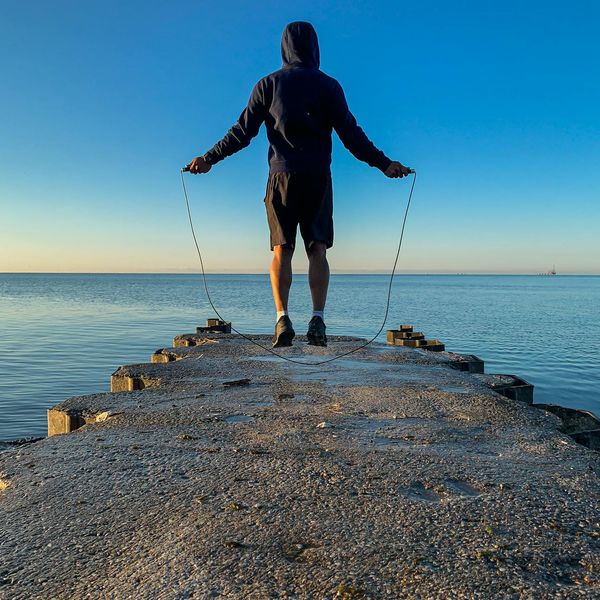 Silhouette of a man stretching against a sunrise, symbolizing renewed energy and well-being.